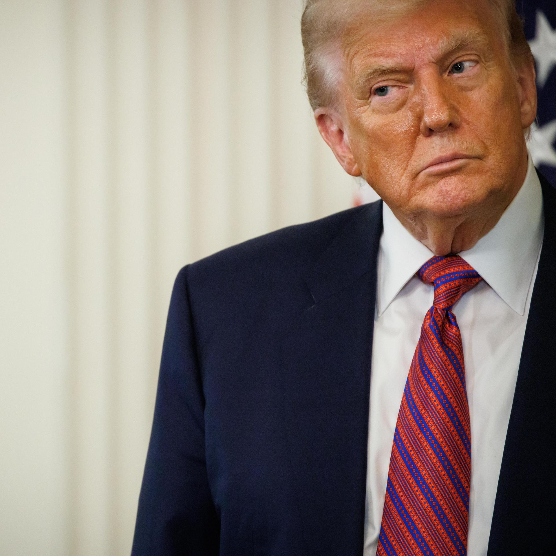 US-Präsident Donald Trump in Anzug und mit Krawatte vor einem hellen Hintergrund schaut skeptisch zur Seite