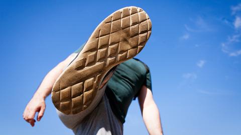 Eine Ansicht von unten wie ein junger Mensch seinen Fuß hoch in die Luft hebt, um jemanden oder etwas zu treten oder zu zertreten. Eine Ansicht von unten wie ein junger Mensch seinen Fuß hoch in die Luft hebt, um jemanden oder etwas zu treten oder zu zertreten.