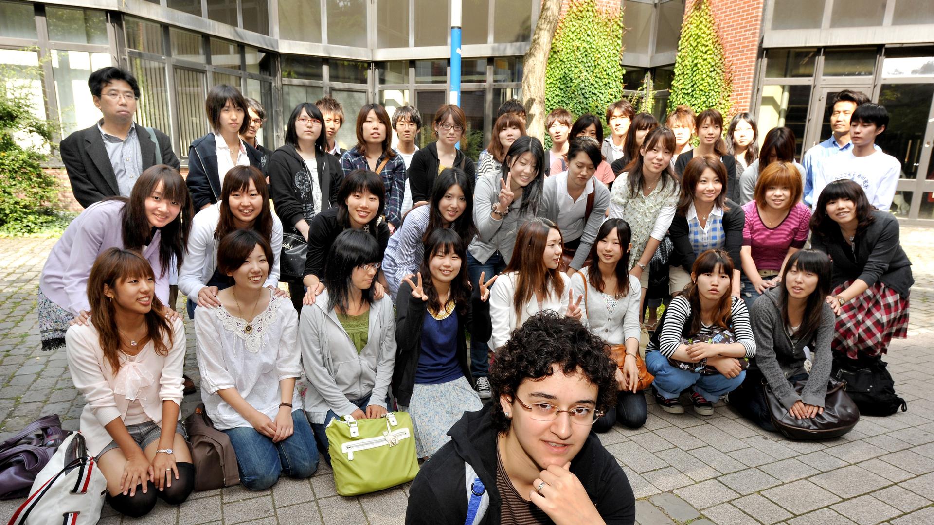 Eine Gruppe international Studierende hocken für ein Foto zusammen. Eine Gruppe international Studierende hocken für ein Foto zusammen.