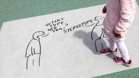 Szene auf de rdocumenta 2022 in Kassel. Auf dem Boden ist als künstlerische Intervention eine comicartige Zeichung mit zwei Strichmännchen zu sehen. Der eine fragt "What type are you?. Der andere antwortet "Stereotype"