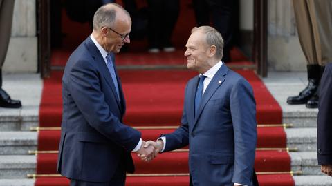 Der polnische Ministerpräsident Donald Tusk (rechts) begrüßt auf einem roten Teppich per Handschlag den neu gewählten deutschen Bundeskanzler Friedrich Merz am 7. Mai 2025 vor dem Regierungsgebäude in Warschau. 