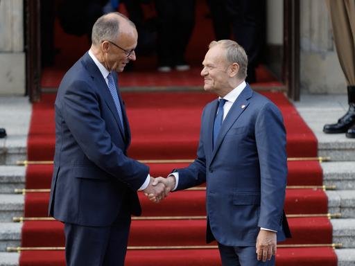 Der polnische Ministerpräsident Donald Tusk (rechts) begrüßt auf einem roten Teppich per Handschlag den neu gewählten deutschen Bundeskanzler Friedrich Merz am 7. Mai 2025 vor dem Regierungsgebäude in Warschau. 