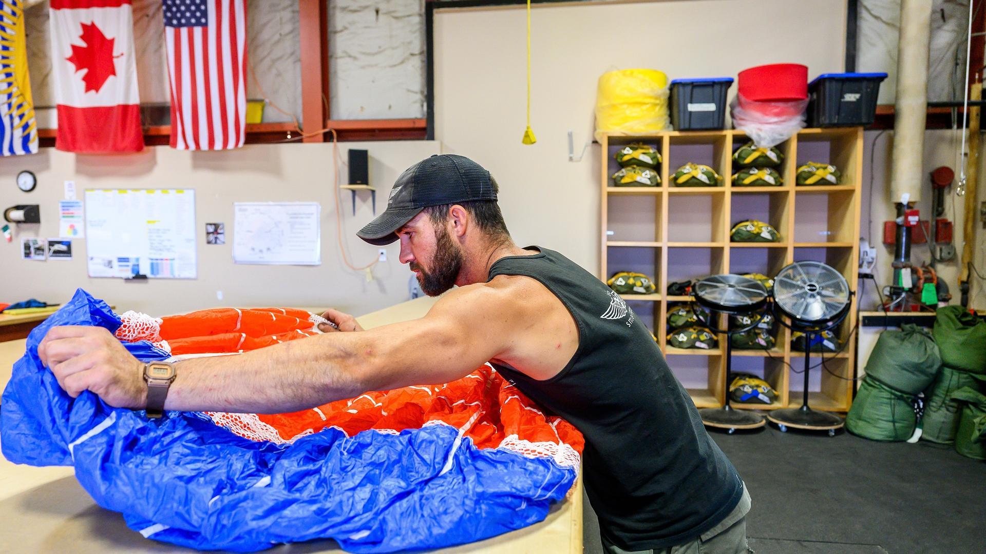 Ein "Smokejumper" packt seinen Fallschirm. Im Hintergrund hängen die kanadische und die us-amerikanische Flagge. Ein "Smokejumper" packt seinen Fallschirm. Im Hintergrund hängen die kanadische und die us-amerikanische Flagge.