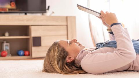 Ein Mädchen liegt auf dem Boden und nutzt ein Tablet