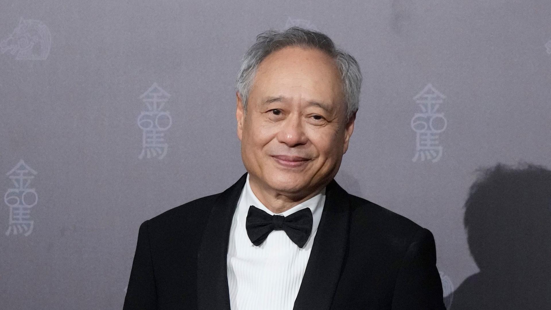 Der Filmemacher Ang Lee aus Taiwan in Abendgarderobe mit Fliege bei einer Preisverleihung vor grauem Hintergrund Der Filmemacher Ang Lee aus Taiwan in Abendgarderobe mit Fliege bei einer Preisverleihung vor grauem Hintergrund