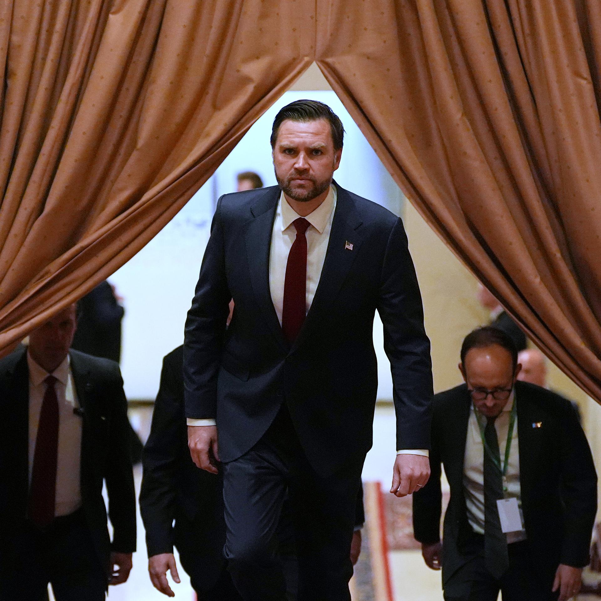 J.D. Vance kommt mit ernster Miene hinter einem Vorhang hervor