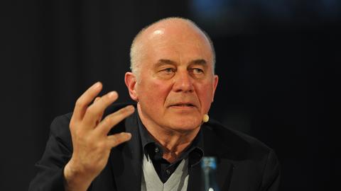 Ein älterer Herr spricht und betont das Gesagte mit seiner Hand.