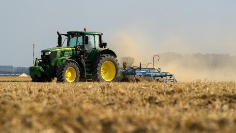Ein Traktor wirbelt Staub auf auf einem gelben, trockenen Feld