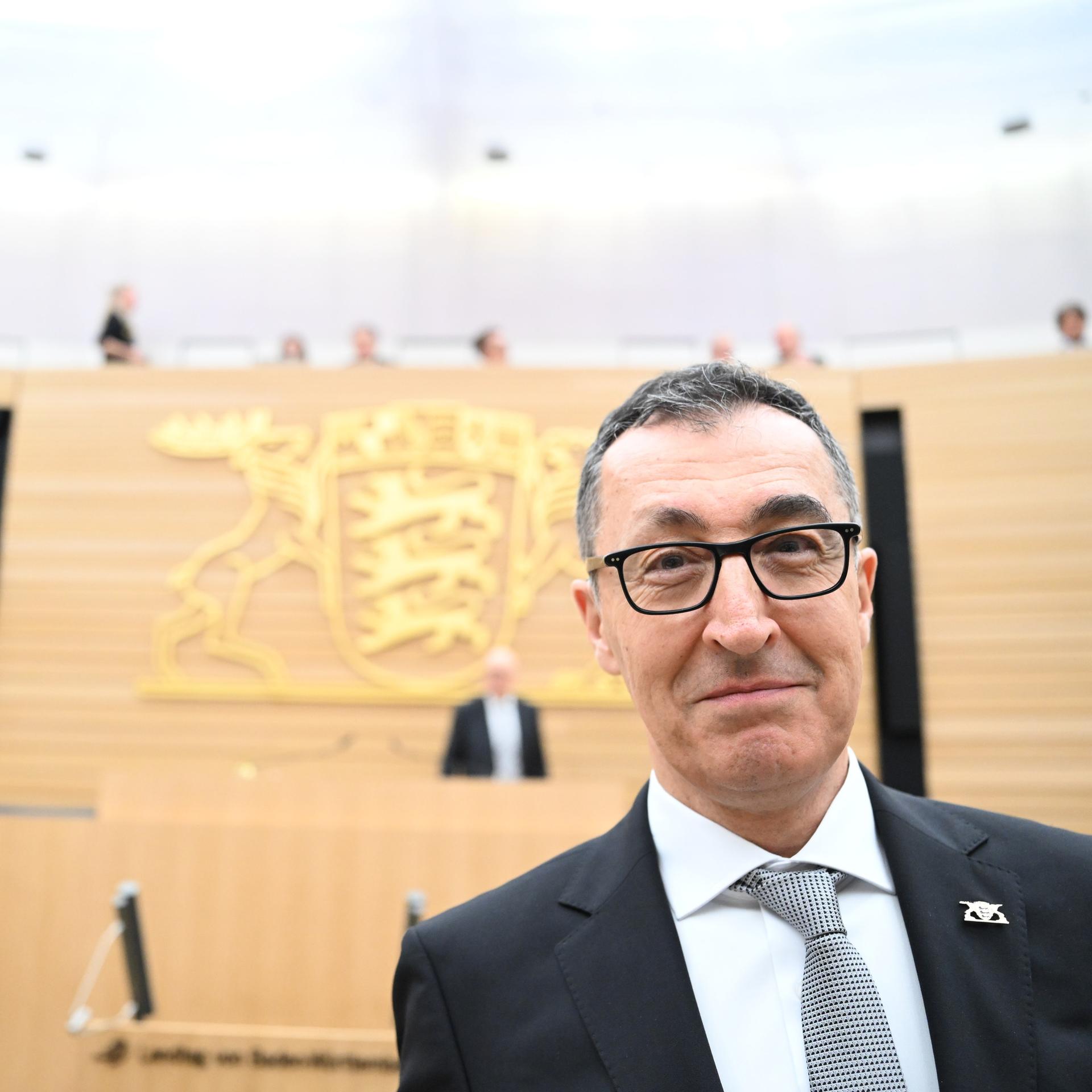 Cem Özdemir steht im Landtag in Stuttgart und lächelt in die Kamera.