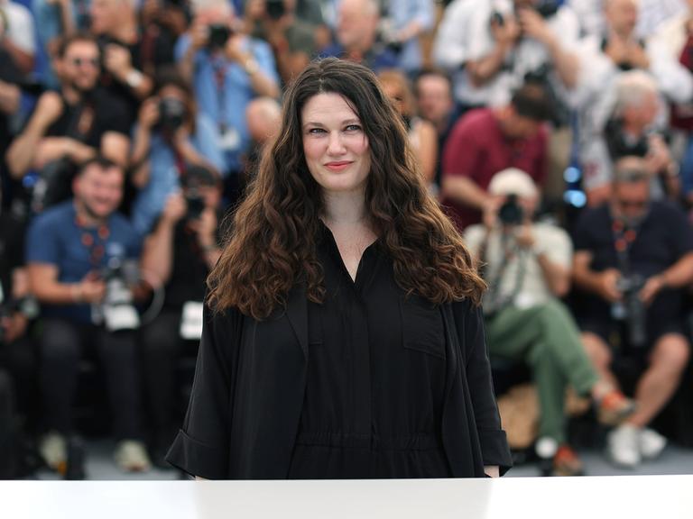 Die deutsche Regisseurin Mascha Schilinski posiert beim Fototermin ihres Films in Cannes für die Fotografen. Im Hintergrund ist eine Menschenmenge zu sehen.