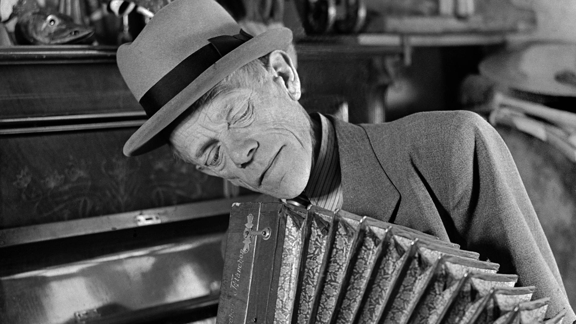 Karl Valentin spielt mit nachdenklichem Gesicht Akkordeon