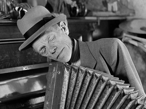 Karl Valentin spielt mit nachdenklichem Gesicht Akkordeon