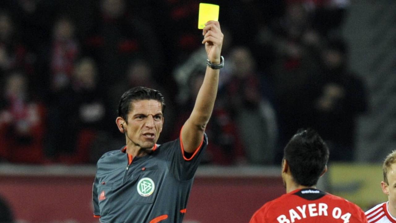 Das Foto zeigt Bundesliga-Schiedsrichter Deniz Aytekin. Er zeigt einem Spieler die gelbe Karte.