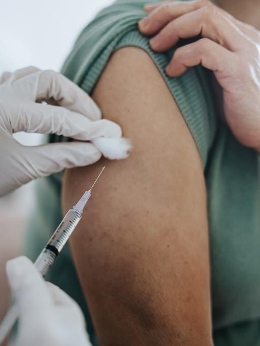 Nahaufnahme eines Armes in den ein Covid-Impfstoff injiziert wird