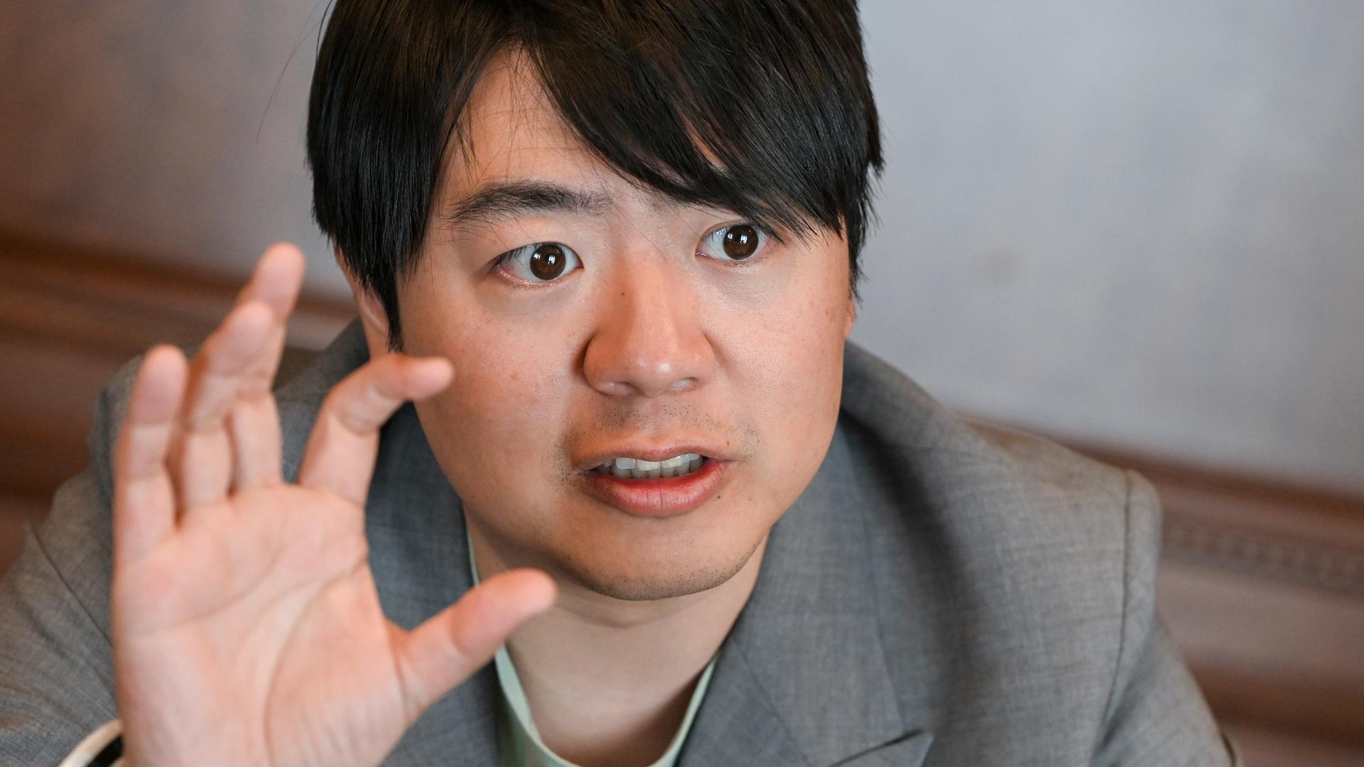 Der Pianist Lang Lang bei einem Interview, wobei er seine rechte Hand zu einem Griff in die Luft ausholt. Der Pianist Lang Lang bei einem Interview, wobei er seine rechte Hand zu einem Griff in die Luft ausholt.