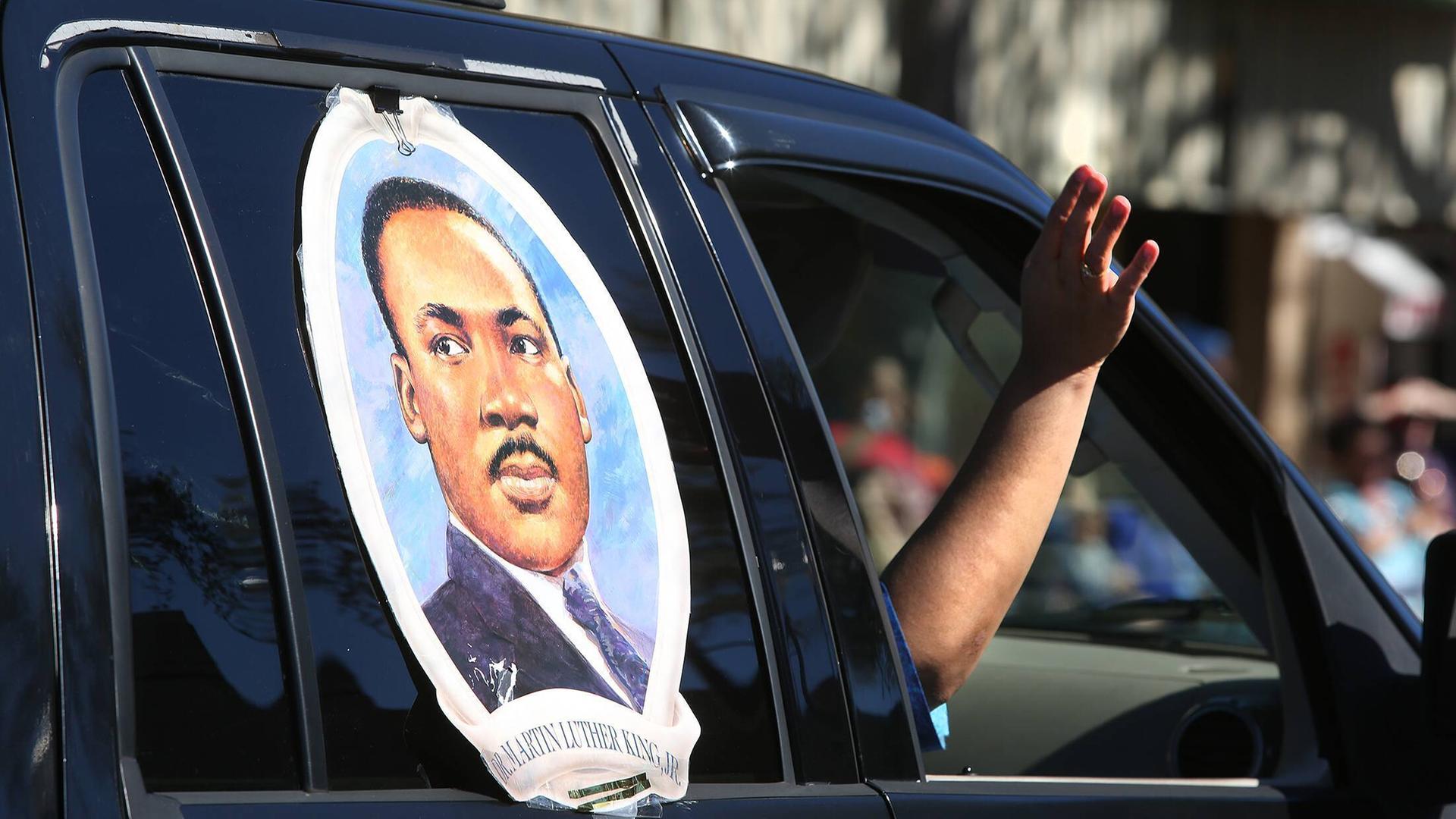 Ein großer Aufkleber mit dem Gesicht von Martin Luther King klebt auf einem Autofenster. Der Beifahrer streckt den Arm aus dem Fenster.