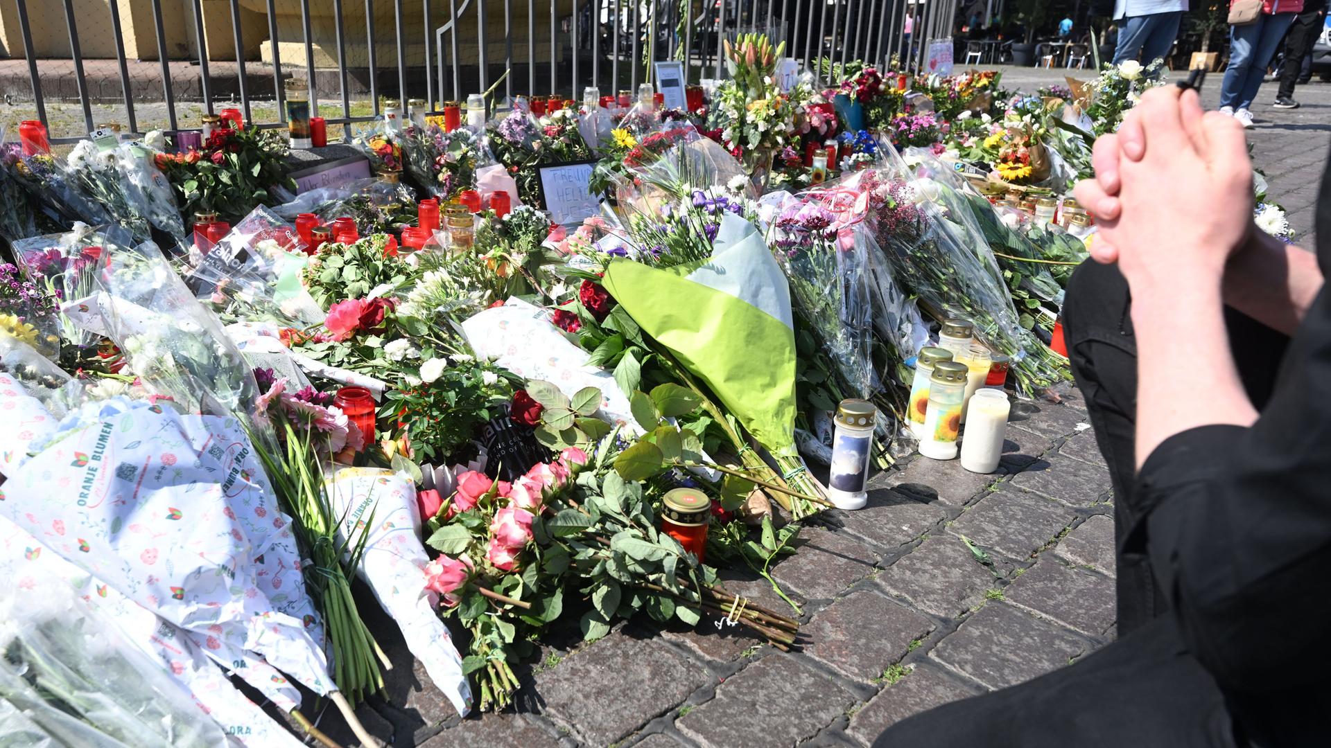 Betende Hände vor Blumensträußen und Kerzen