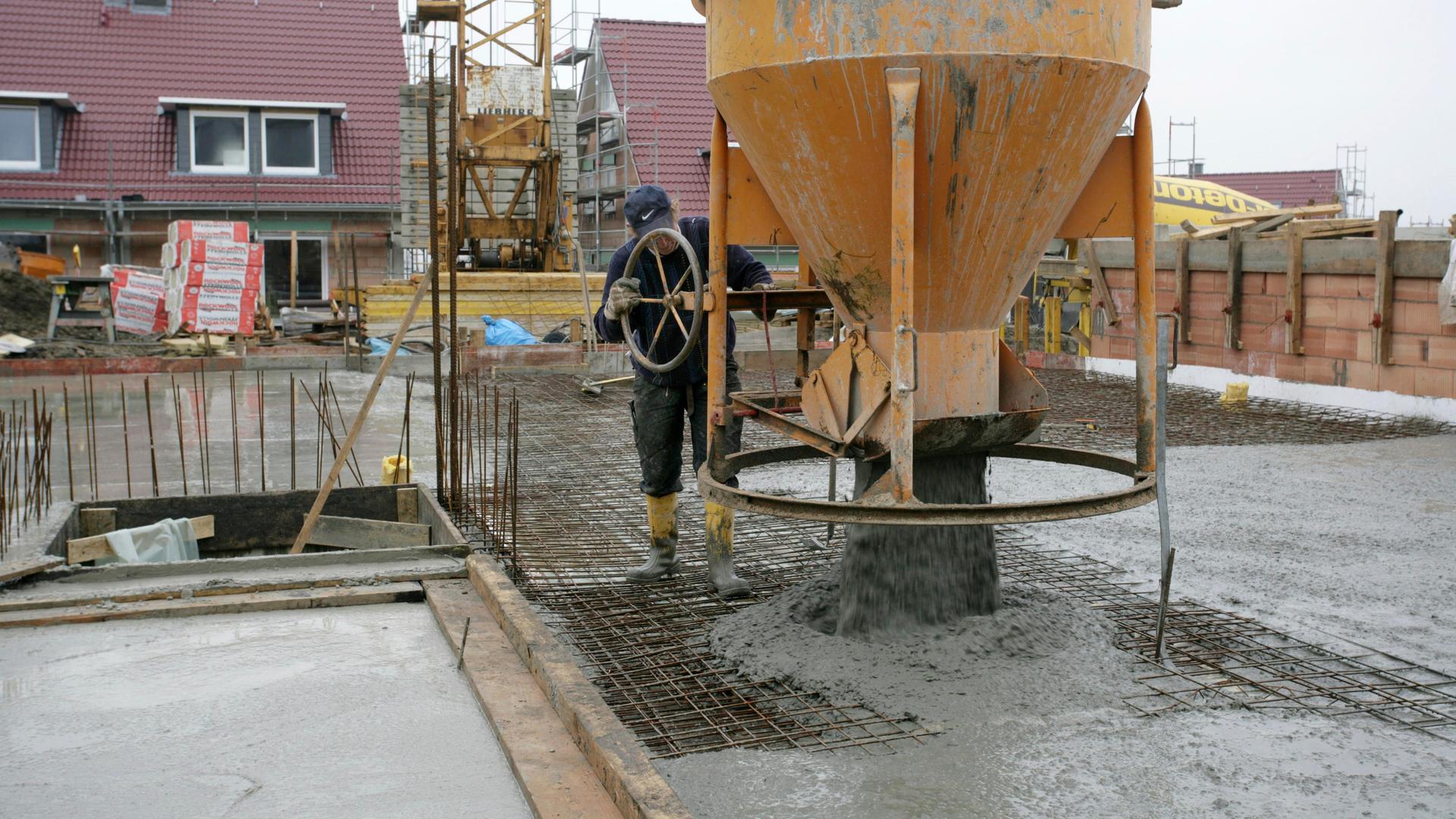 Ein Bauarbeiter lässt flüssigen Beton aus einem großen Behälter ab.