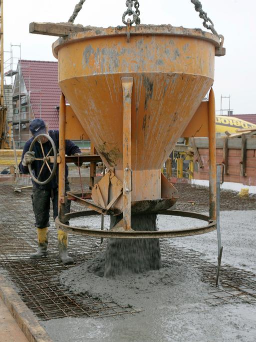 Ein Bauarbeiter lässt flüssigen Beton aus einem großen Behälter ab.