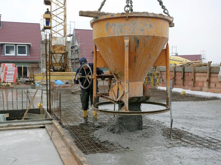 Ein Bauarbeiter lässt flüssigen Beton aus einem großen Behälter ab.