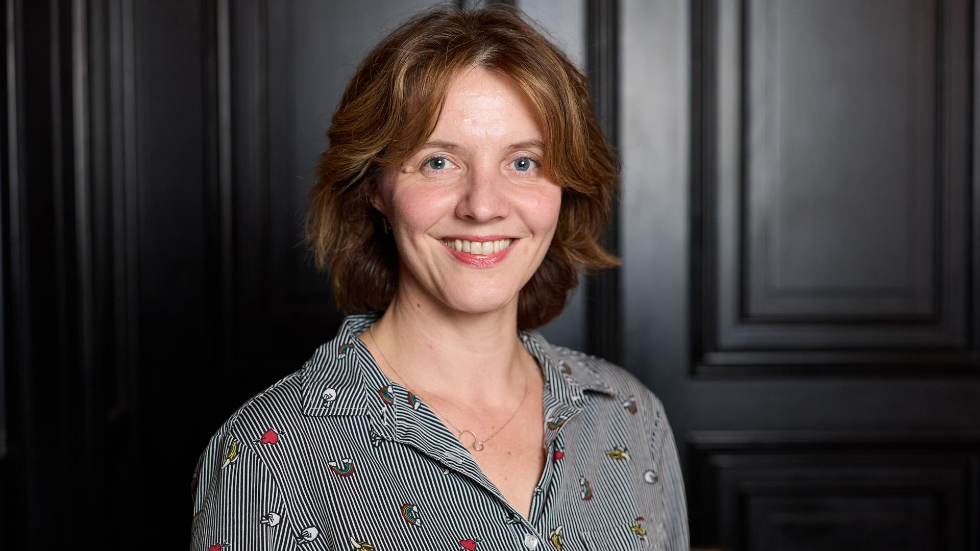 Peggy Mädler, Dramaturgin und Regisseurin, steht anlässlich des 10. Longlist-Abends zum Deutschen Buchpreis im Literaturhaus Hamburg und lächelt in die Kamera.