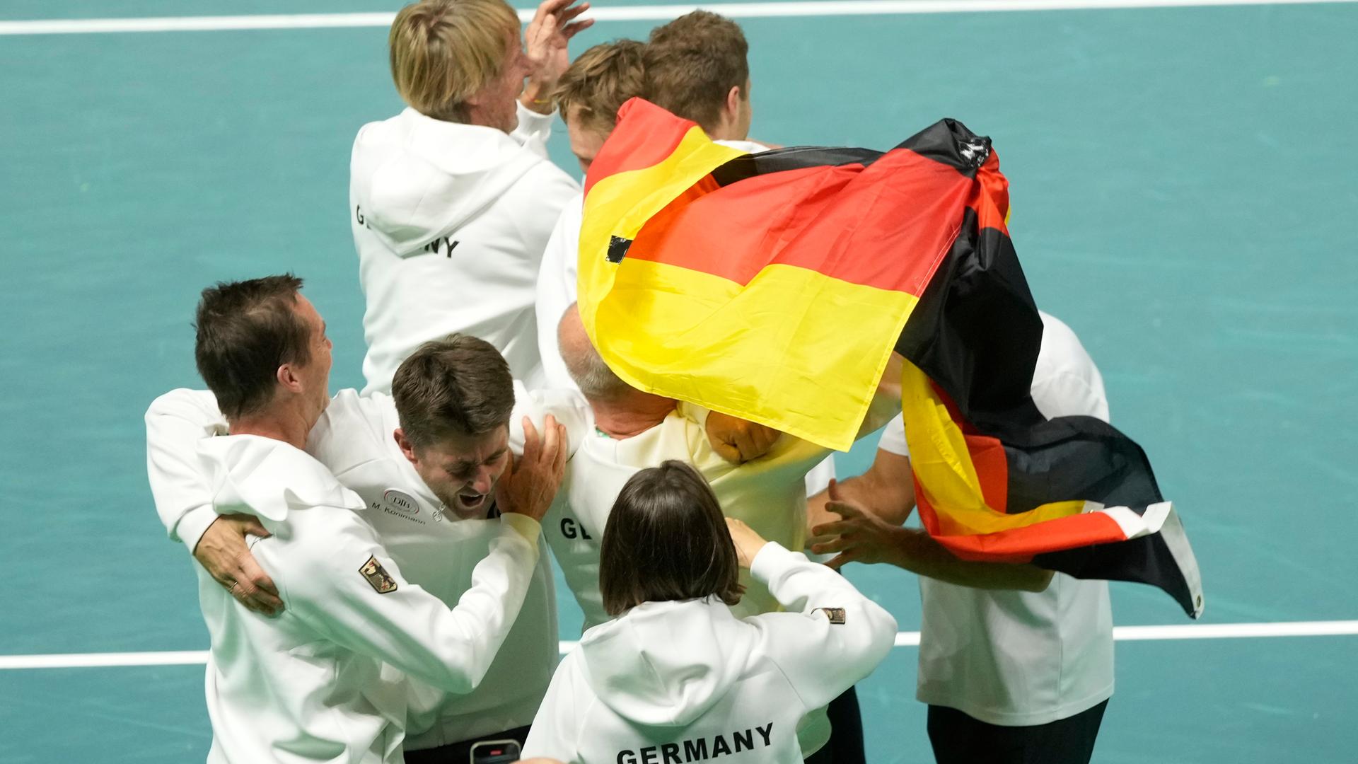 Menschen liegen sich in den Armen. Einer hebt eine Deutschlandfahne hoch.