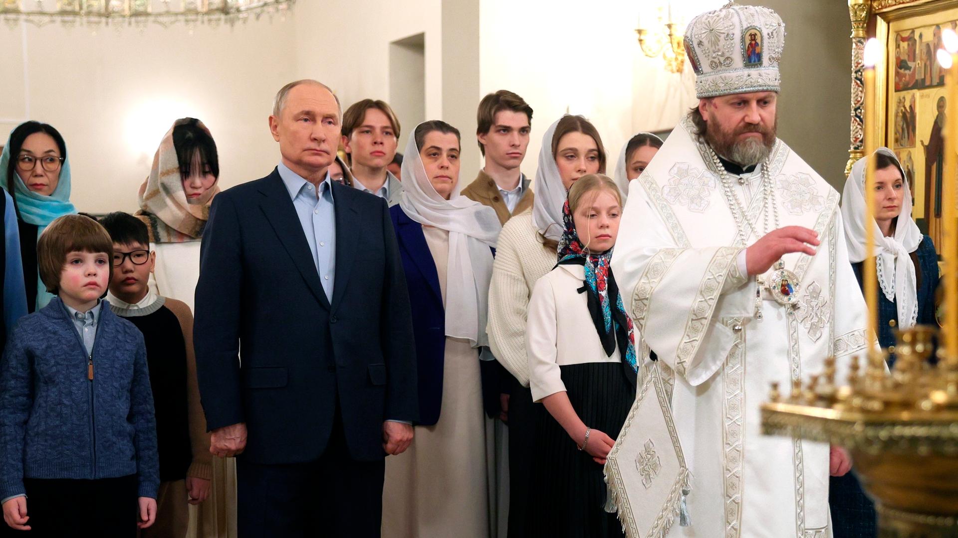 Russlands Präsident Wladimir Putin (mitte links) wohnt gemeinsam mit den Familien von gefallenen Soldaten einem orthodoxen Weihnachtsgottesdienst bei.