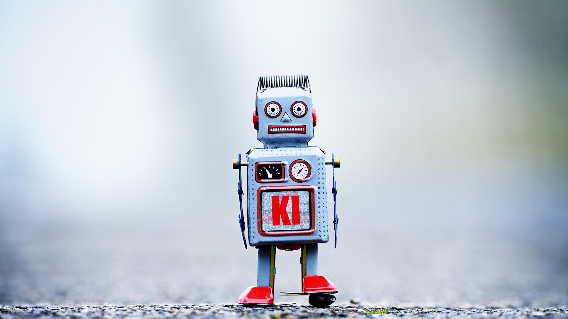 Eine Fotomontage zeigt eine Roboterfigur mit der Aufschrift KI. 