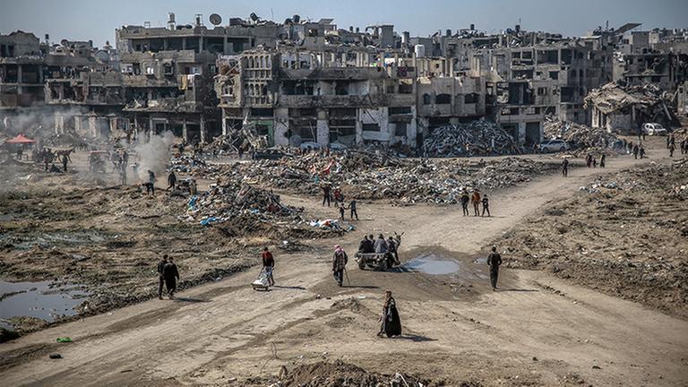 Menschen gehen über ein von israelischen Luftschlägen zerstörtes urbanes Gebiet im Norden des Gazastreifens. (Archivbild)