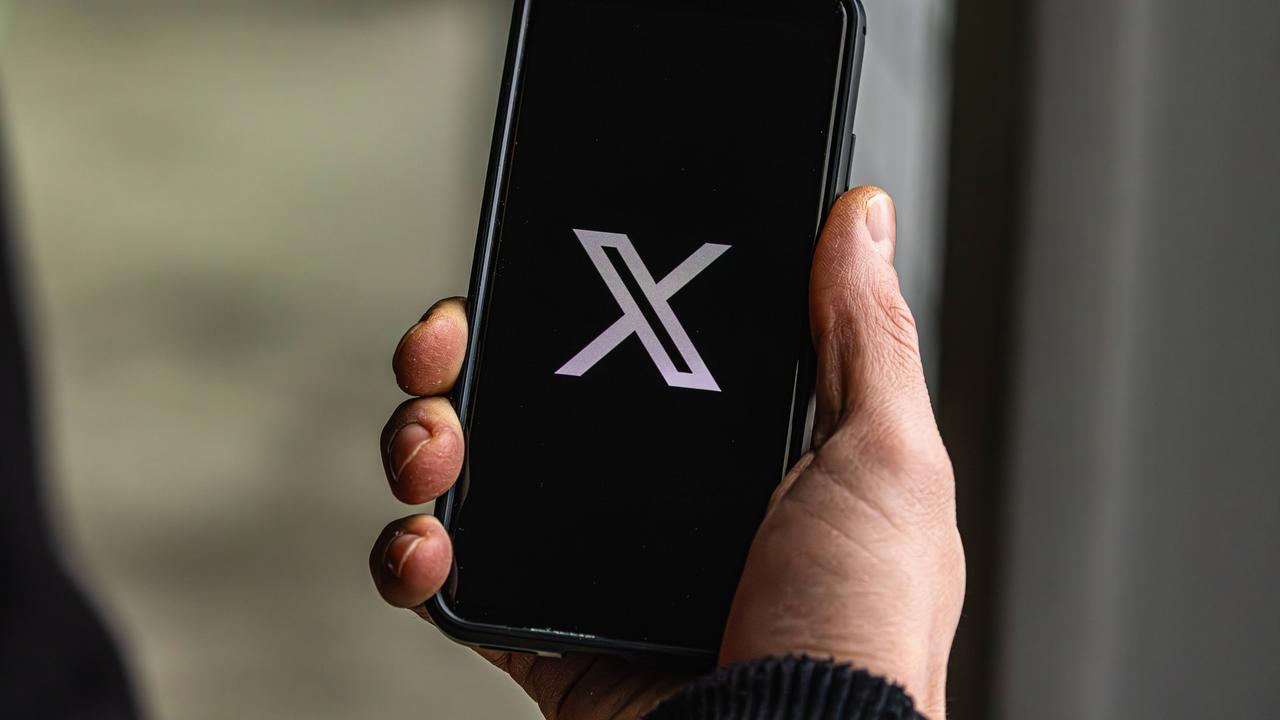 Jemand hält ein Handy in der Hand, auf dem die Plattform "X" geöffnet wird.