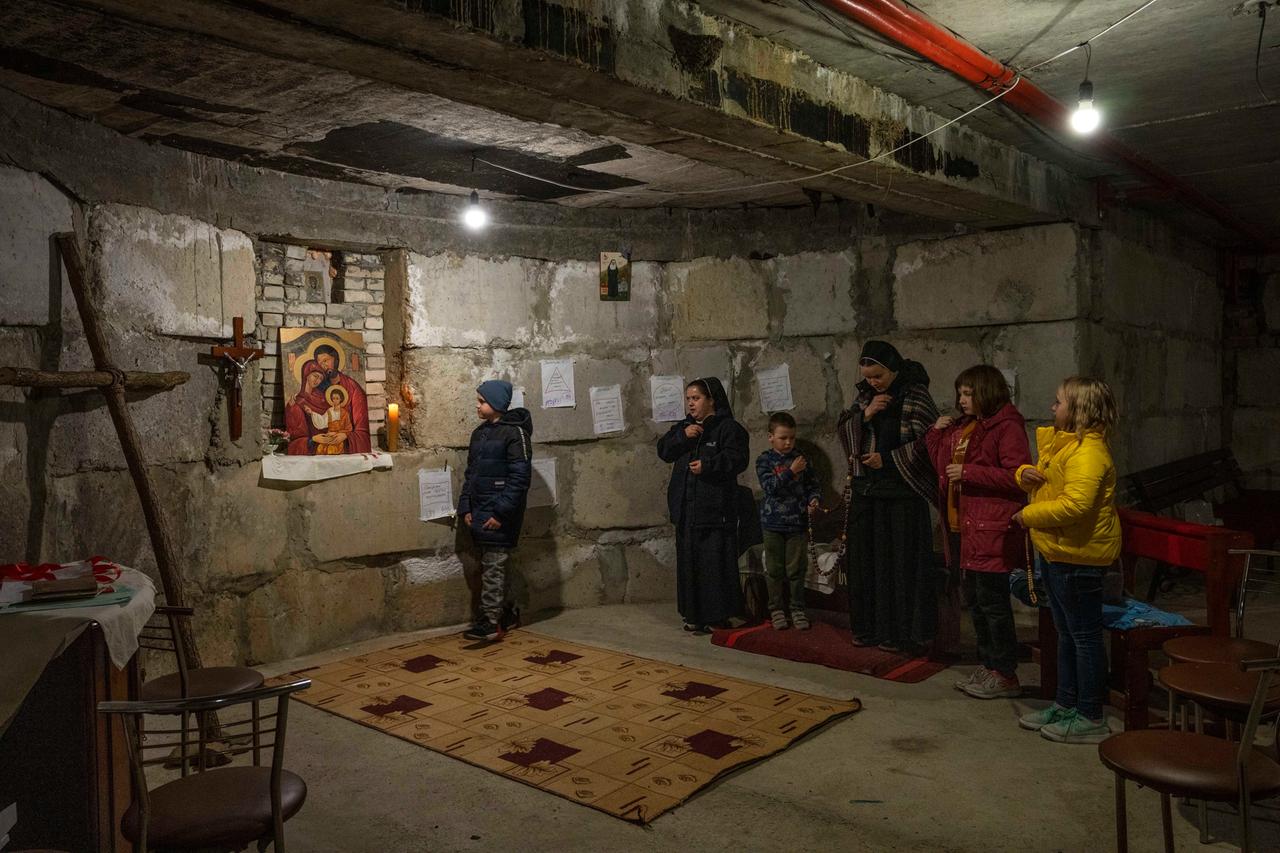 Ukraine, Iwano-Frankiwsk: Der 10-jährige Rostyslav Borysenko, der aus dem belagerten Mariupol geflohen ist (l), und vertriebene Kinder beten mit Nonnen in einer behelfsmäßigen Kapelle in einem Keller.