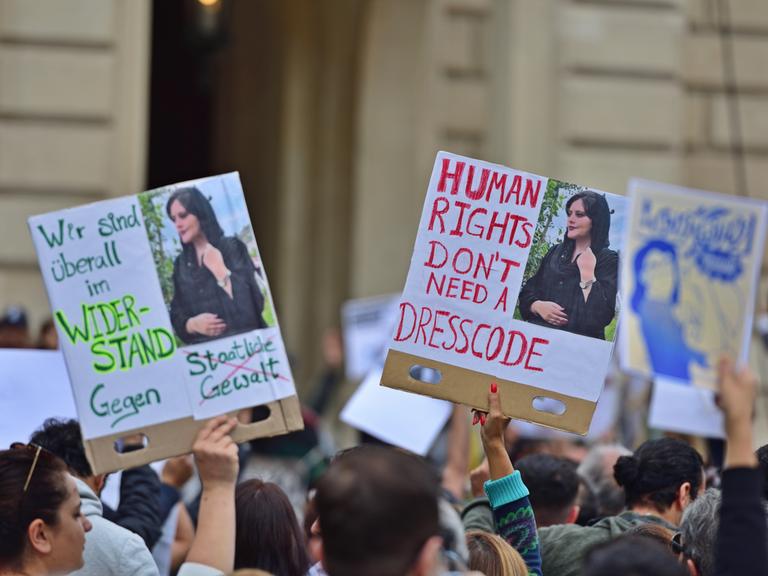 Protest in Frankfurt am Main infolge des Todes der jungen Iranerin Mahsa Amini. Plakate mit einem Foto und dem Schriftzug "Human Rights don't need a dresscode" werden von Demonstrierenden in die Höhe gehalten. Die Proteste richten sich gegen das Mullah-Regime in Teheran.