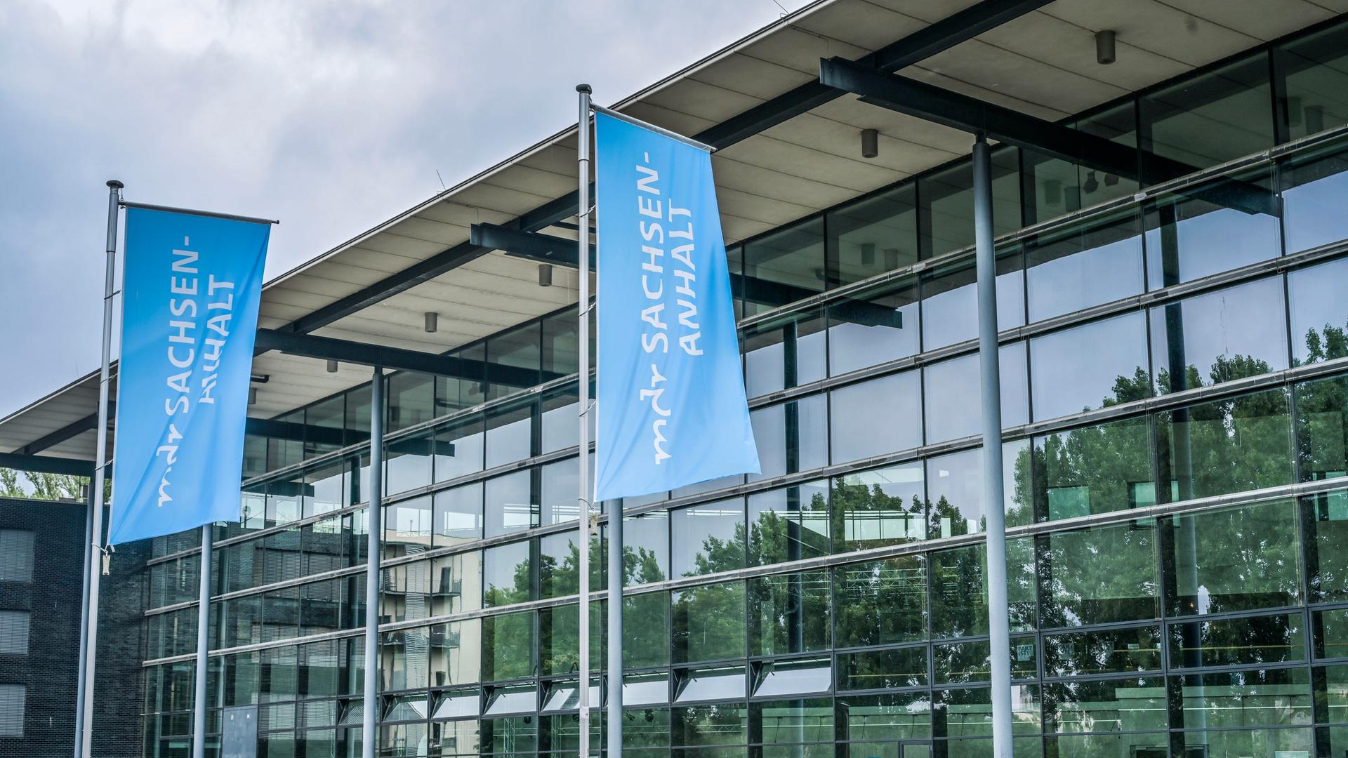 Blick auf das gläserne MDR-Landesfunkhaus in Magdeburg. Davor blaue Flaggen mit der Aufschrift "mdr Sachsen-Anhalt" Blick auf das gläserne MDR-Landesfunkhaus in Magdeburg. Davor blaue Flaggen mit der Aufschrift "mdr Sachsen-Anhalt"