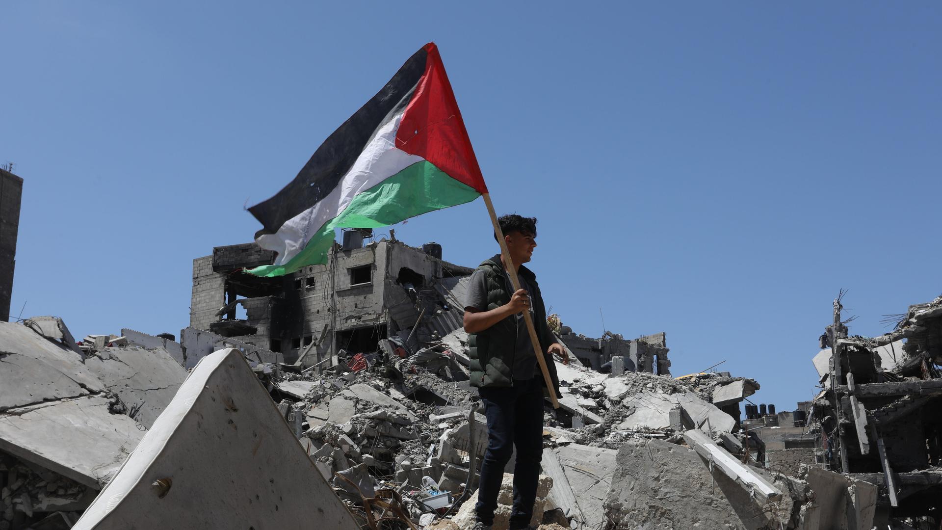 Mann mit palästinensischer Flagge auf den Trümmern im Gazastreifen am 13. April 2024