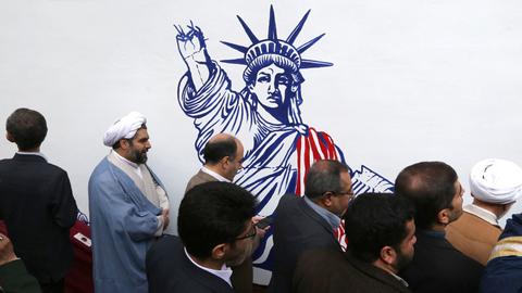 Iranische Männer vor dem Wandgemälde an der ehemaligen US-Botschaft in der Hauptstadt Teheran, die Freiheitsstatue wird mit abgehacktem Arm gezeigt.