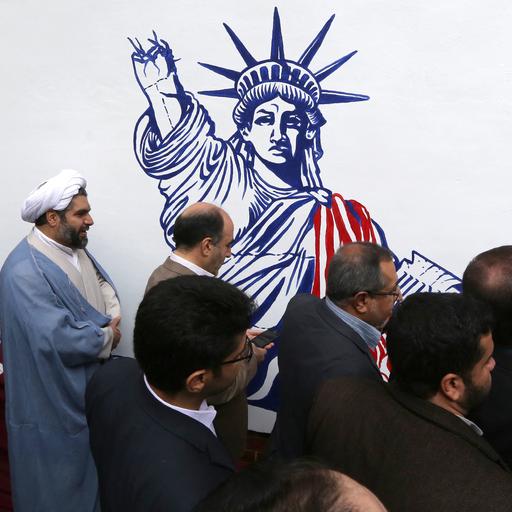 Iranische Männer vor dem Wandgemälde an der ehemaligen US-Botschaft in der Hauptstadt Teheran, die Freiheitsstatue wird mit abgehacktem Arm gezeigt.