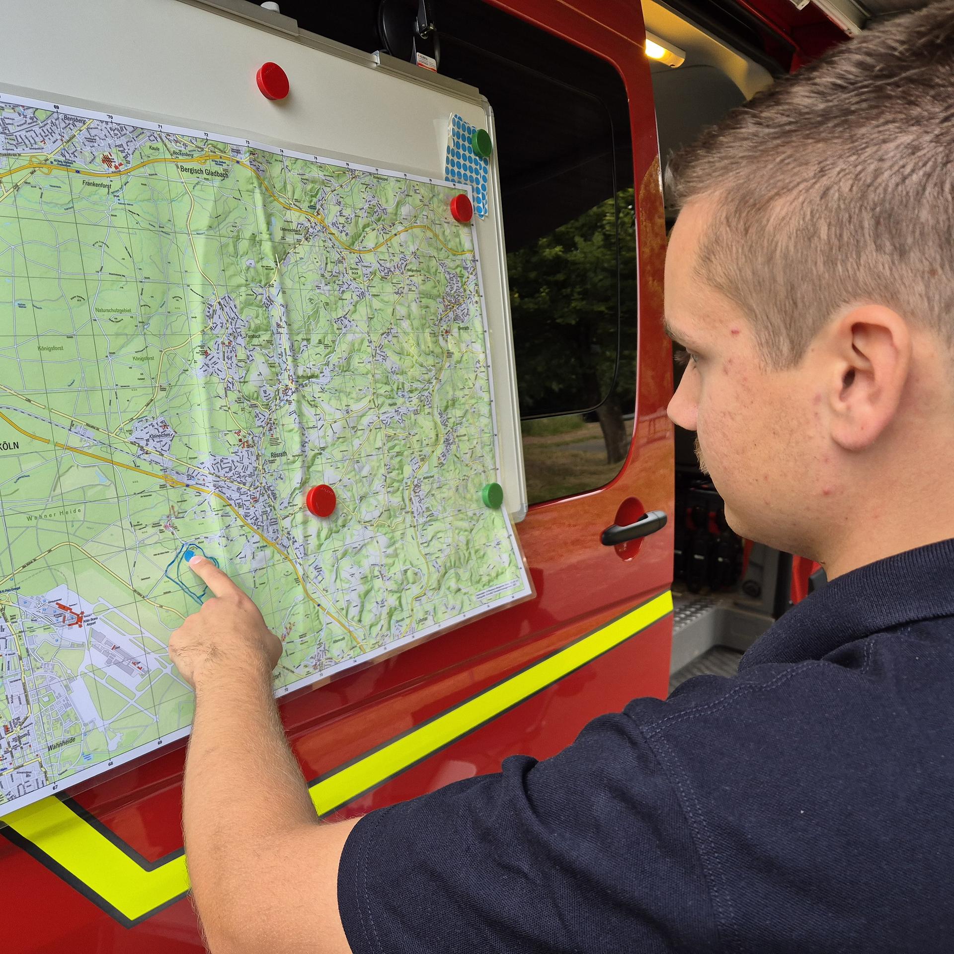 Rösrath: Ein Feuerwehrmann zeigt auf die markierte Brandstelle auf einer Karte. 