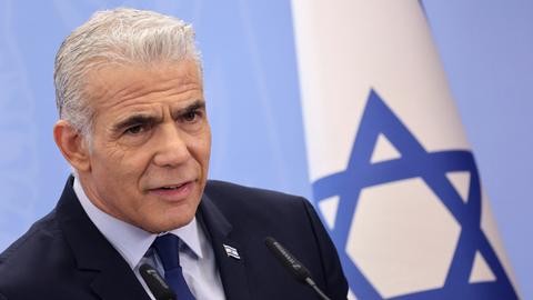 Israels Oppositionsführer Jair Lapid steht vor einer israelischen Flagge.