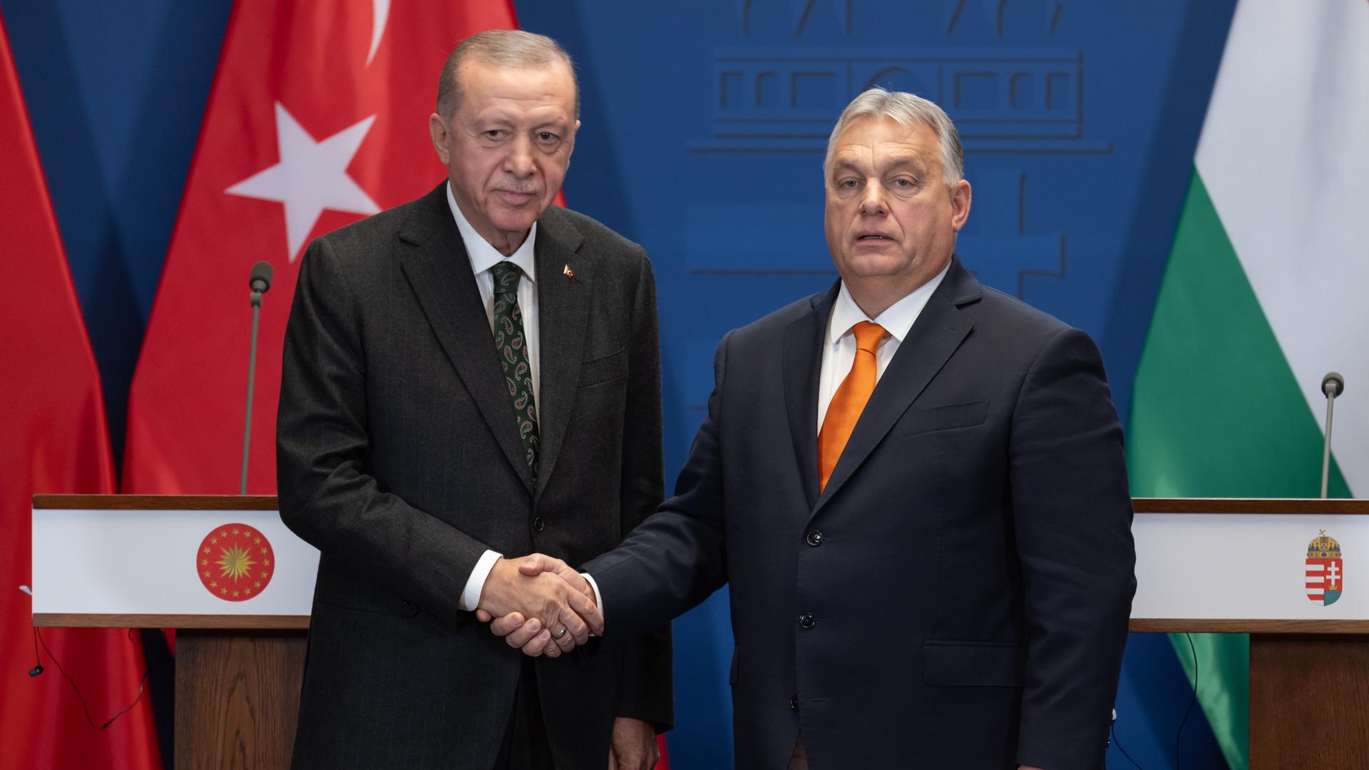 Recep Tayyip Erdogan und Viktor Orban schütteln Hände vor Rednerpulten und aufgestellten Flaggen.