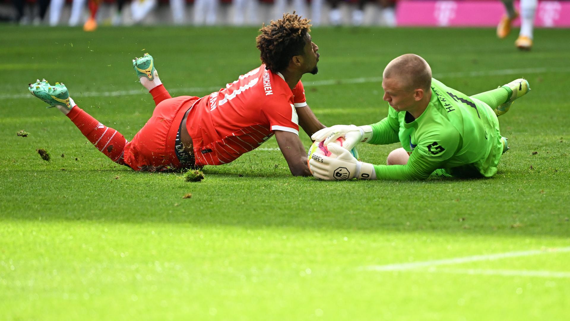 FC-Bayern-Spieler Kingsley Coman und Hertha-Torwart Oliver Christensen kämpfen um den Ball.