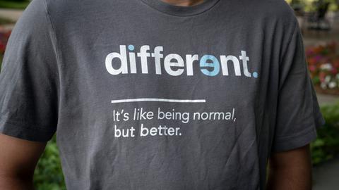 "Anders ist so wie Normalsein – nur besser," steht in weißen Buchstaben auf Englisch auf dem dunkelgrauen T-Shirt eines jungen Mannes. 