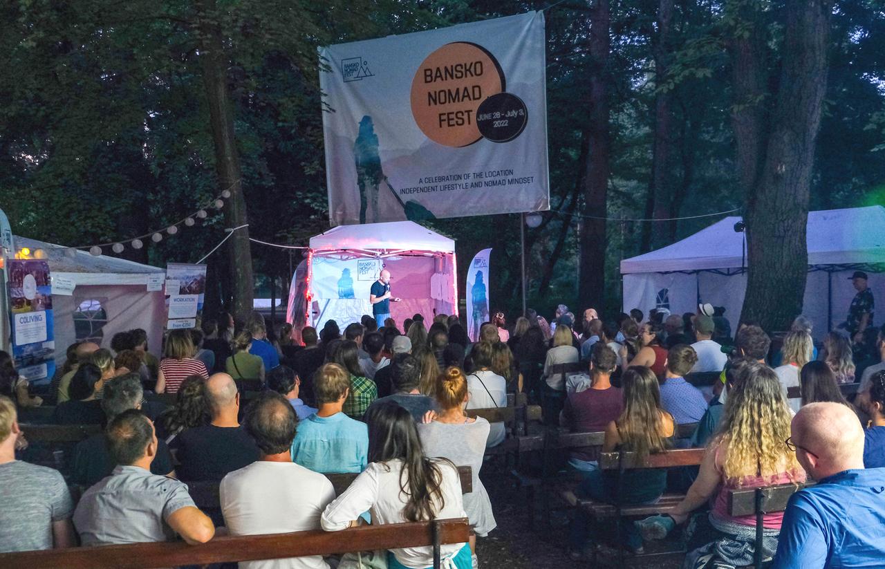 Letzter Abend beim Bansko Nomad Festivals. Menschen sitzen im Freien auf Bänken und schauen auf eine kleine Bühne. 