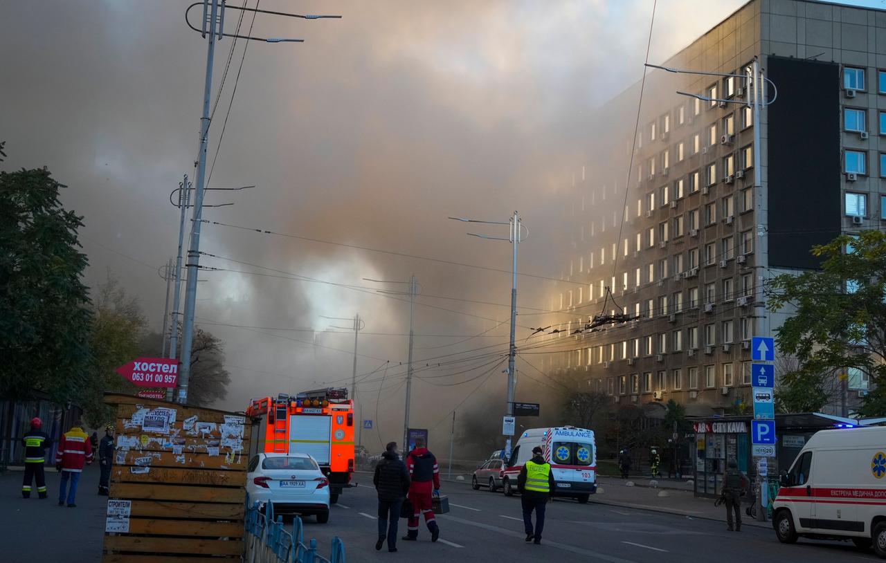 Rauch vernebelt die Sicht in einer Straße in Kiew. Es sind Rettungskräfte unterwegs.