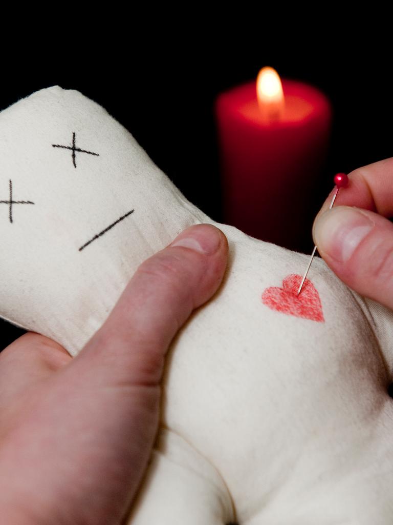 ILLUSTRATION: Eine Frau steckt steckt eine Nadel ins Herz einer Voodoo-Puppe.