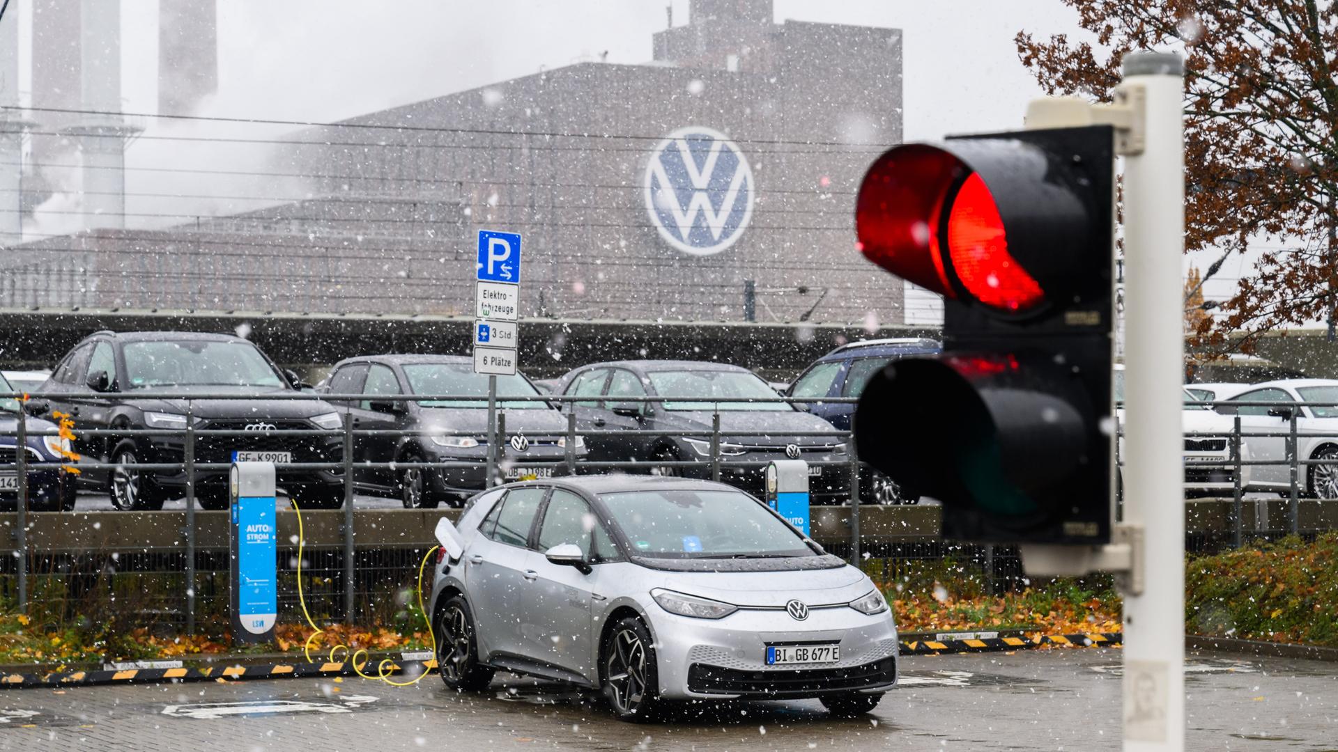 Ein Volkswagen ID.3 lädt in Sichtweite des Heizkraftwerkes am Volkswagen-Werk Wolfsburg - zu sehen ist auch eine roten Ampel. 