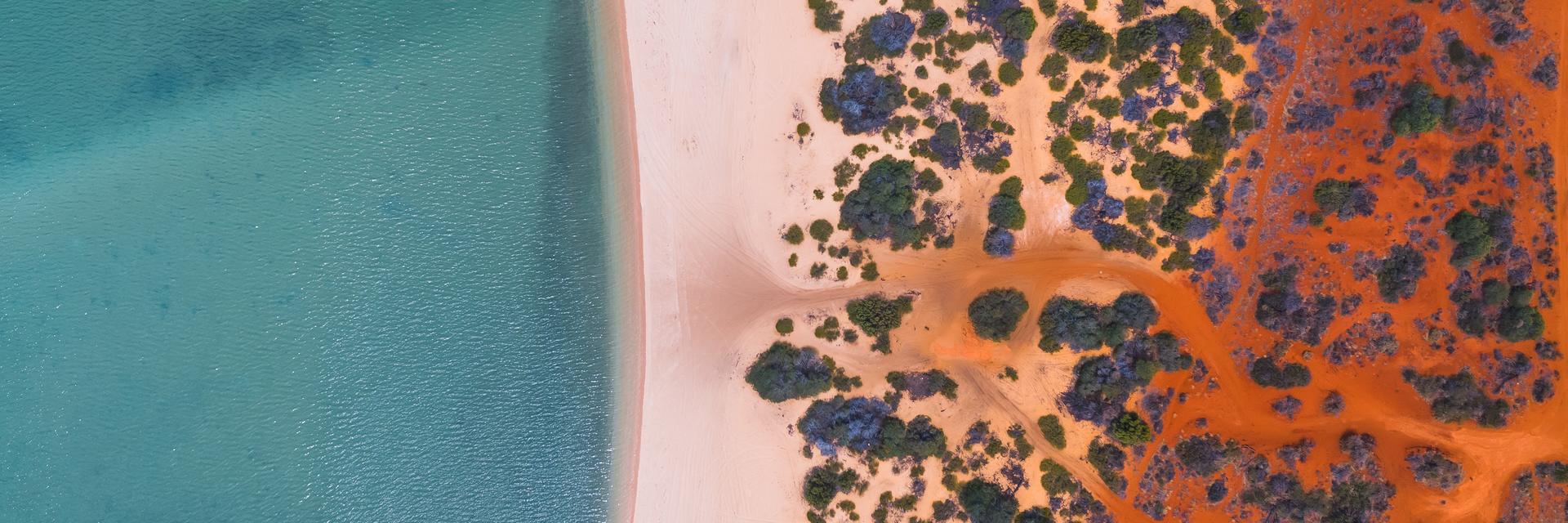 Luftaufnahme eines Strandes in Australien. Durch die Färbung des Wassers und der Wüste, ähnelt die Aufnahme Klimastreifen.