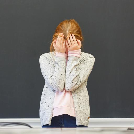 Frustriertes Mädchen in einer Prüfung an der Tafel der Grundschule schämt sich