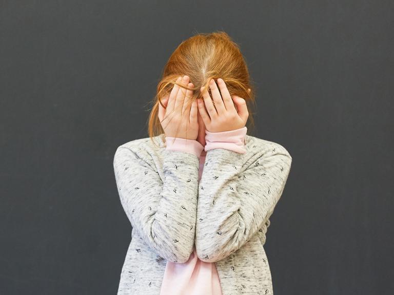 Frustriertes Mädchen in einer Prüfung an der Tafel der Grundschule schämt sich