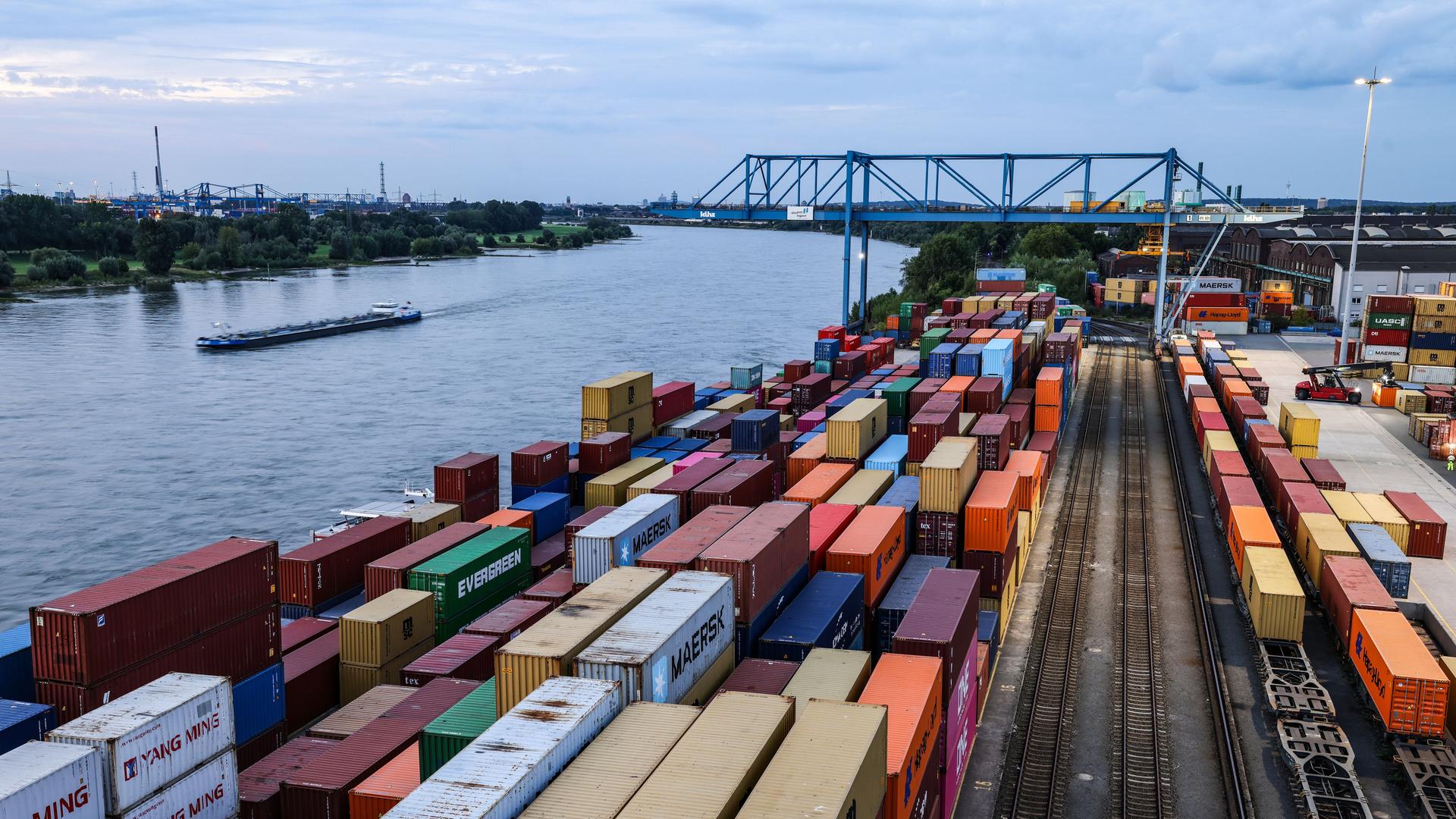 Container stehen im Duisburger Hafen am Kai: Im Containerterminal Logport 2 werden Güter von der Schiene auf Binnenschiffe umgeschlagen. Links im Bild ist ein Fluss zu sehen, auf dem ein Schiff fährt. Container stehen im Duisburger Hafen am Kai: Im Containerterminal Logport 2 werden Güter von der Schiene auf Binnenschiffe umgeschlagen. Links im Bild ist ein Fluss zu sehen, auf dem ein Schiff fährt.