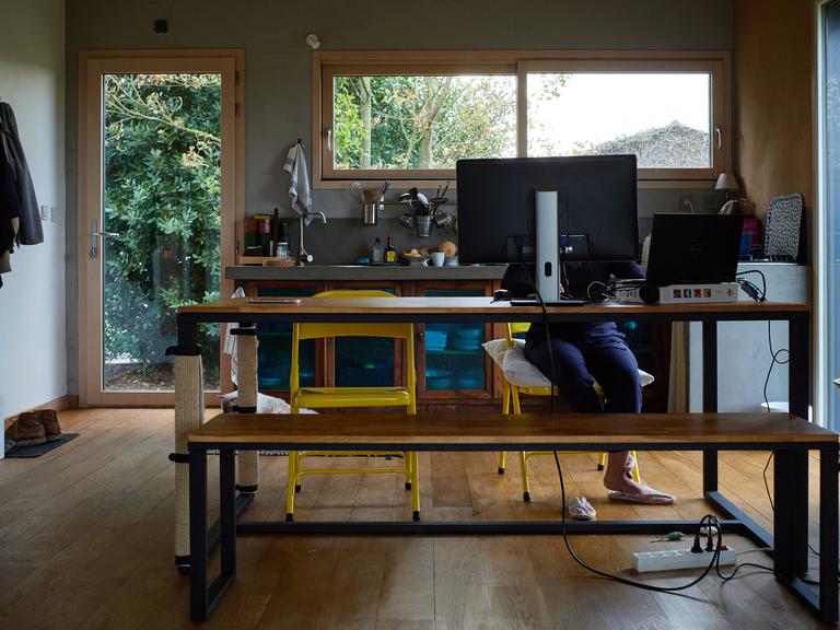 Eine Person sitzt in einer Küche am Computer und arbeitet.